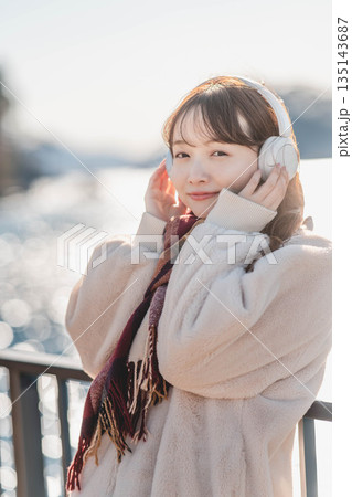 海辺に立ちヘッドホンで音楽を聴く若い女性 135143687