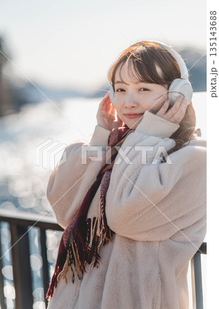 海辺に立ちヘッドホンで音楽を聴く若い女性 海辺に立ちヘッドホンで音楽を聴く若い女性 135143688