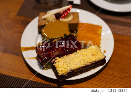 A Delightful Assortment of Colorful Cakes on a Plate, Showcasing Various Flavors and Textures with Rich Toppings and Creamy Layers to Tempt Every Sweet Tooth A Delightful Assortment of Colorful Cakes on a Plate, Showcasing Various Flavors and Textures with Rich Toppings and Creamy Layers to Tempt Every Sweet Tooth 135143822