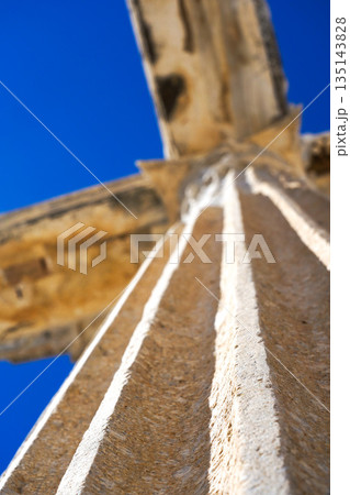 A Dramatic Perspective of an Ancient Column Under a Clear Blue Sky with Detailed Texture and Architectural Features Highlighted in Beautiful Lighting 135143828