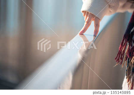 海辺に立つ女性の手元 135143895