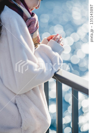 海辺に立つ女性の手元 135143897