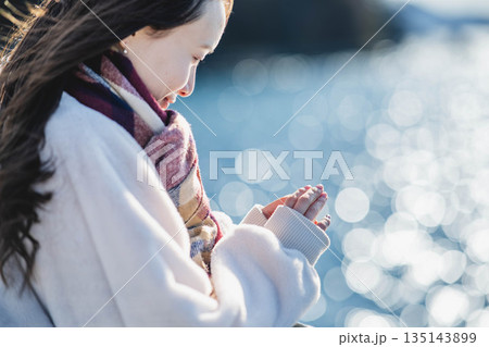 海辺に立つ女性の手元 135143899