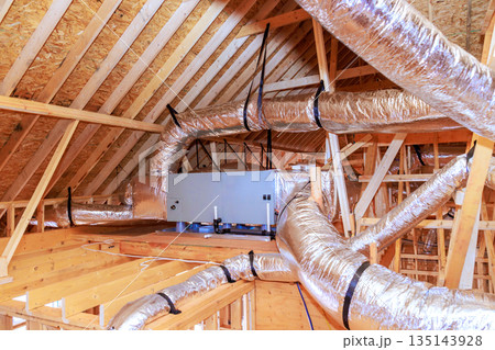 Workers install ducting ventilation systems in attic space of house under construction. Workers install ducting ventilation systems in attic space of house under construction. 135143928