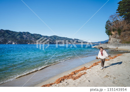 海辺を歩く若い女性 海辺を歩く若い女性 135143954