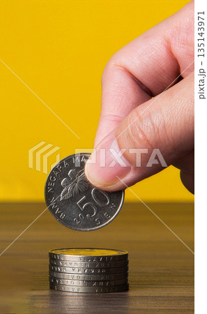 Hand stacking malaysian 50 sen coin for savings Hand stacking malaysian 50 sen coin for savings 135143971