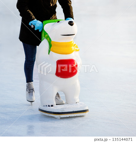 Skater helpers to keeps balance on ice. Woman ion figure skates with learning figure on ice rink Skater helpers to keeps balance on ice. Woman ion figure skates with learning figure on ice rink 135144071