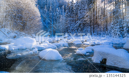 Peaceful winter river flowing through a snow covered forest during gentle snowfall. Soft sunlight reflects on icy water, creating a calm, atmospheric, and serene winter nature scene. Peaceful winter river flowing through a snow covered forest during gentle snowfall. Soft sunlight reflects on icy water, creating a calm, atmospheric, and serene winter nature scene. 135144325