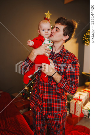 Father holds baby during Christmas celebration at home 135144420