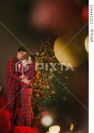 Family in matching outfits by Christmas tree during holiday Family in matching outfits by Christmas tree during holiday 135144421