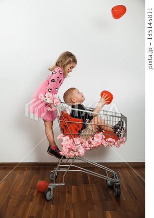 Children play with red balloons in shopping cart at indoor location during daytime 135145811