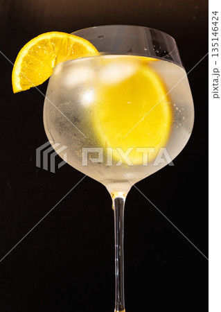 Vertical picture of Gin tonic cocktail with orange slice and ice .Black background 135146424
