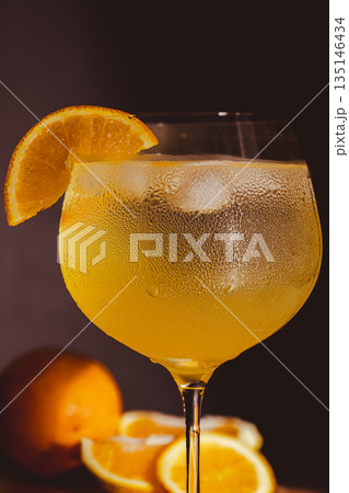 Close-up vertical shot of a drink prepared with gin, tonic and orange slices. Blurred backgrond Close-up vertical shot of a drink prepared with gin, tonic and orange slices. Blurred backgrond 135146434