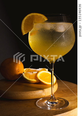 Gin and tonic with orange slice and ice in a glass with dramatic studio lighting 135146436