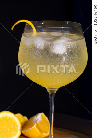 Cold orange gin and tonic with orange peel garnish on a black background. 135146460