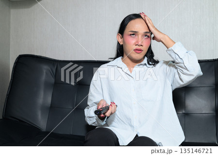 Portrait of a young Thai transgender woman watching television looking stressed Portrait of a young Thai transgender woman watching television looking stressed 135146721