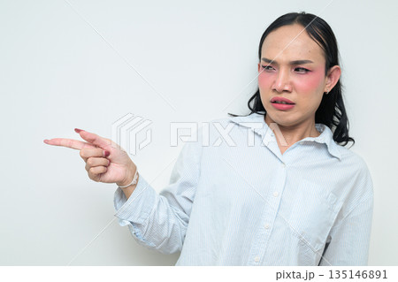 Portrait of young Thai transgender person pointing finger looking annoyed against white background Portrait of young Thai transgender person pointing finger looking annoyed against white background 135146891