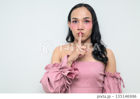 Portrait of a young Thai transgender person against white background with finger on lips 135146996
