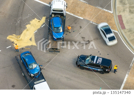 Car crash with tow truck hauling damaged car and first responders helping at accident site on American street. Vehicle collision on road in USA Car crash with tow truck hauling damaged car and first responders helping at accident site on American street. Vehicle collision on road in USA 135147340