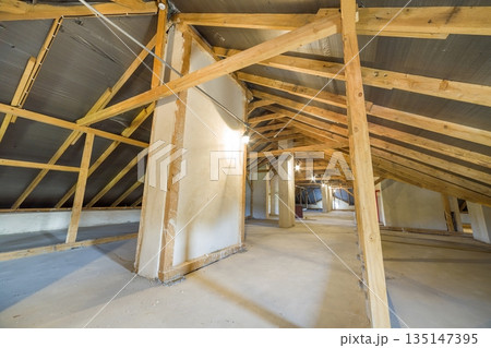 Attic of a building with wooden beams of a roof structure. Attic of a building with wooden beams of a roof structure. 135147395