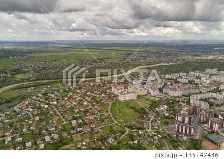 Aerial view of town or city with rows of buildings and curvy streets in summer. Urban landscape from above. Aerial view of town or city with rows of buildings and curvy streets in summer. Urban landscape from above. 135147436