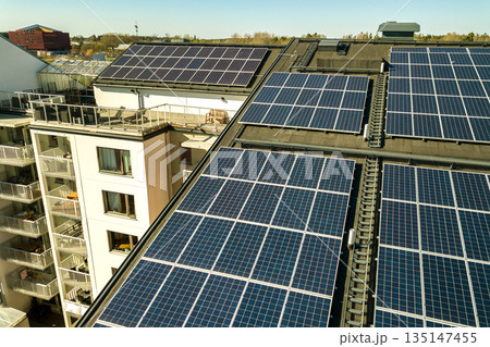 Aerial view of solar photovoltaic panels on a roof top of residential building block for producing clean electric energy. Autonomous housing concept. 135147455