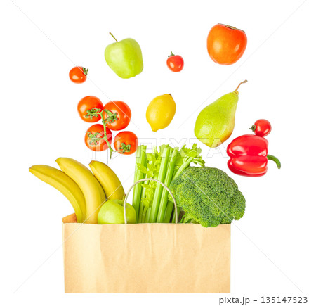 Fresh fruits and vegetables flying above paper grocery bag isolated on white background, healthy food and shopping concept Fresh fruits and vegetables flying above paper grocery bag isolated on white background, healthy food and shopping concept 135147523