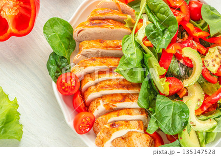 Sliced grilled chicken breast with fresh vegetable salad on white plate 135147528