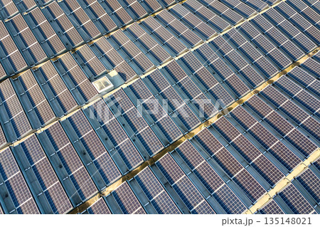 Aerial view of many photo voltaic solar panels mounted of industrial building roof. 135148021