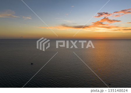 Aerial view of lonesome white yacht at sunset floating on sea waves with ripple surface. Motor boat recreation on ocean surface 135148024