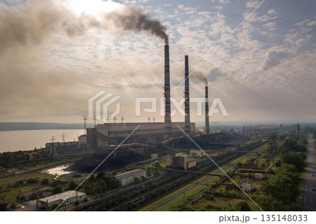 Aerial view of high chimney pipes with grey smoke from coal power plant. Production of electricity with fossil fuel. 135148033