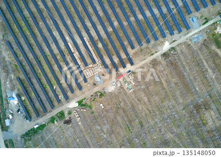 Aerial view of electrical power plant under construction with truck delivering assembly parts for solar panels on metal frame for producing electric energy. Development of renewable electricity Aerial view of electrical power plant under construction with truck delivering assembly parts for solar panels on metal frame for producing electric energy. Development of renewable electricity 135148050