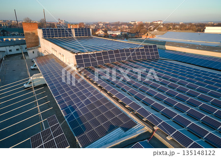 Aerial view of blue photovoltaic solar panels mounted on industrial building roof for producing green ecological electricity. Production of sustainable energy concept 135148122