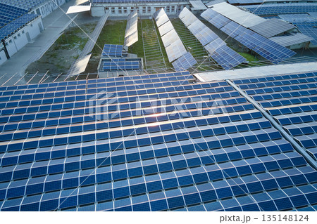 Aerial view of blue photovoltaic solar panels mounted on industrial building roof for producing green ecological electricity. Production of sustainable energy concept 135148124