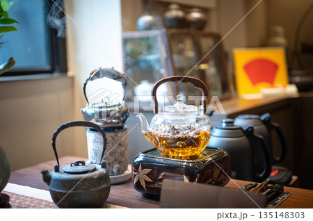 Elegant Kettle Boiling Tea With Flowers And Green Scenery 135148303