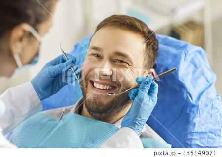 Happy smile of man in dentist chair during professional oral exam procedure 135149071