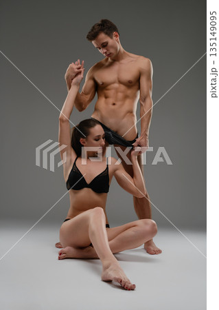 Passionate couple in black underwear posing together in an intimate studio portrait. 135149095