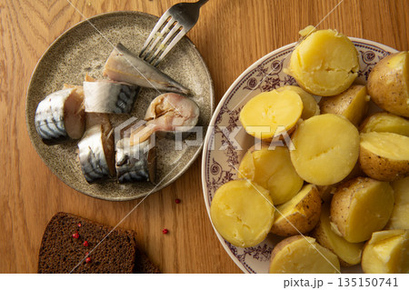Sliced mackerel and boiled potatoes served on wooden table with rye bread 135150741