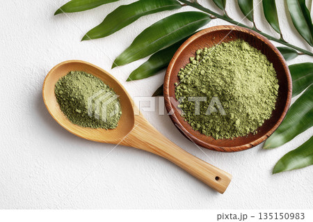 Green matcha herbal powder in wooden bowl and spoon with fresh leaves, perfect for cosmetics mock-up 135150983