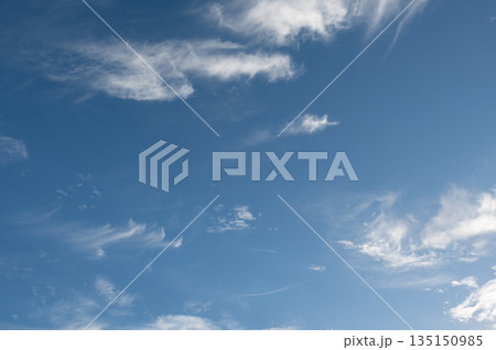 Wispy cirrus clouds drifting across a vibrant blue sky 135150985