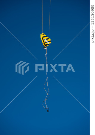 Crane hook hanging with steel cable on blue sky background 135150989