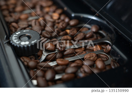 Coffee beans filling coffee machine container, ready for grinding Coffee beans filling coffee machine container, ready for grinding 135150990