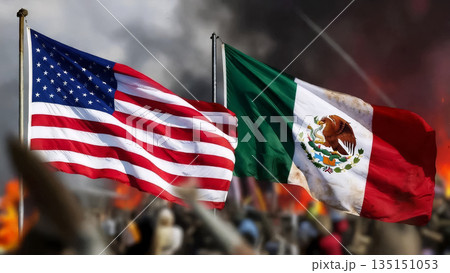 usa and mexico flags waving against a backdrop of smoke and a blurred crowd of people 135151053