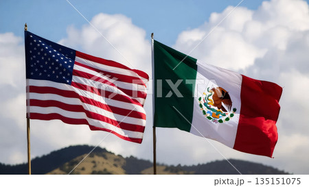 american and mexican flags waving against fluffy white clouds and distant mountain peaks 135151075
