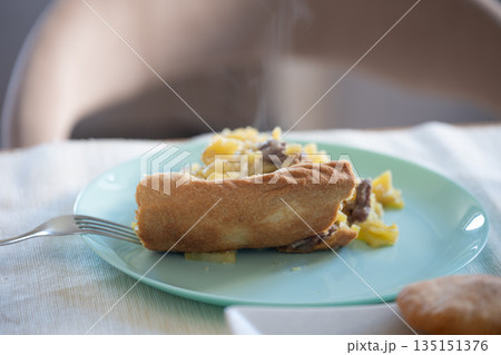 Steaming slice of homemade meat and potato pie on light blue plate with fork Steaming slice of homemade meat and potato pie on light blue plate with fork 135151376