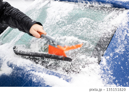 Person quickly removing ice from vehicle, Frosty morning routine to clear icy windshield safely Person quickly removing ice from vehicle, Frosty morning routine to clear icy windshield safely 135151820