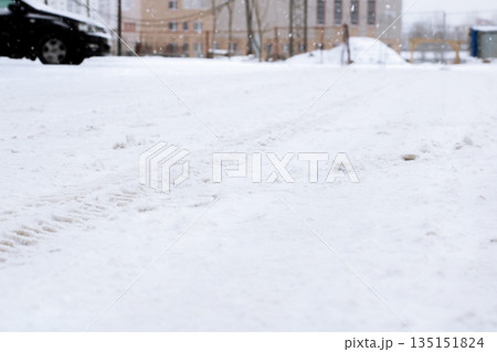 City street blanketed in snow, Quiet urban road covered with snow and scattered tracks 135151824