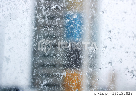 Perspective of office worker observing snowencrusted cityscape through icy window Perspective of office worker observing snowencrusted cityscape through icy window 135151828