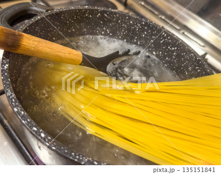 Pasta Cooking Scene, Homestyle Cooking Moment With Golden Noodles Simmering In Pot Of Hot Water Pasta Cooking Scene, Homestyle Cooking Moment With Golden Noodles Simmering In Pot Of Hot Water 135151841
