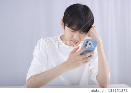 リビングでスマホを見て落胆する若い男性 リビングでスマホを見て落胆する若い男性 135151871